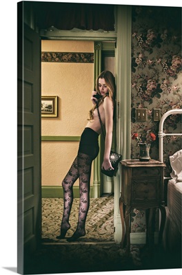 Woman wearing stockings and talking on the telephone in her hotel bedroom