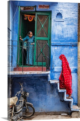 Woman with red Sari walking up steps in the blue city of Jodphur