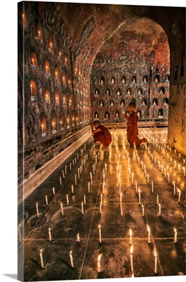 Young monk praying with candles in his monastery in Myanmar
