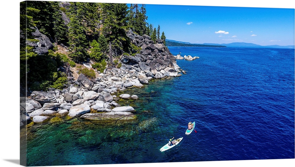 2 paddle boarders explore the west shore of lake Tahoe. Location: Lake Tahoe, California.