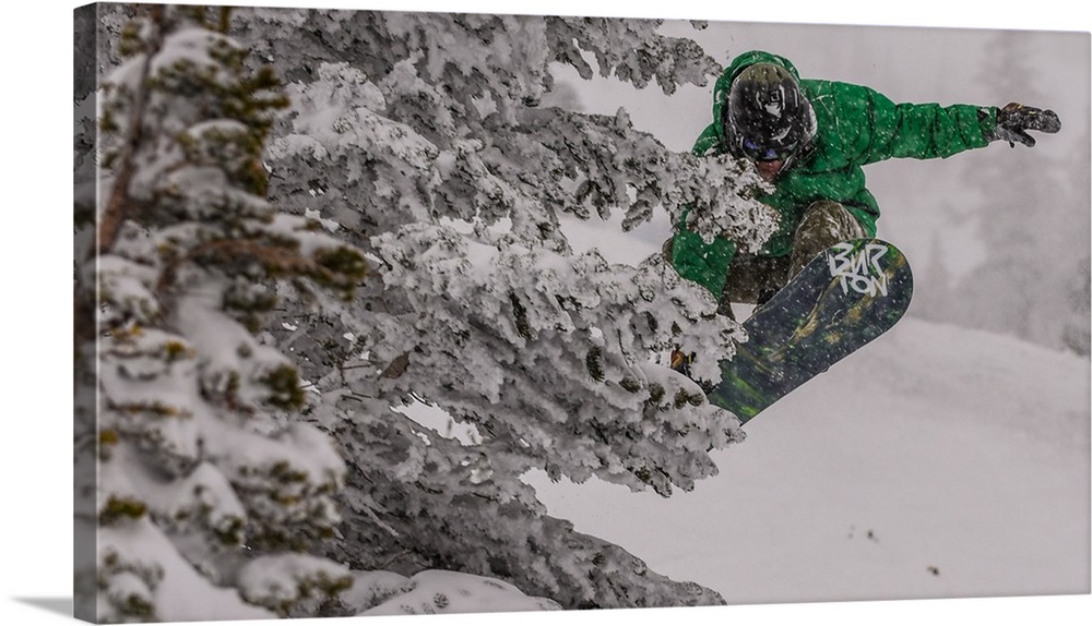 Action shot of a snowboarder in green doing a grab mid-air.