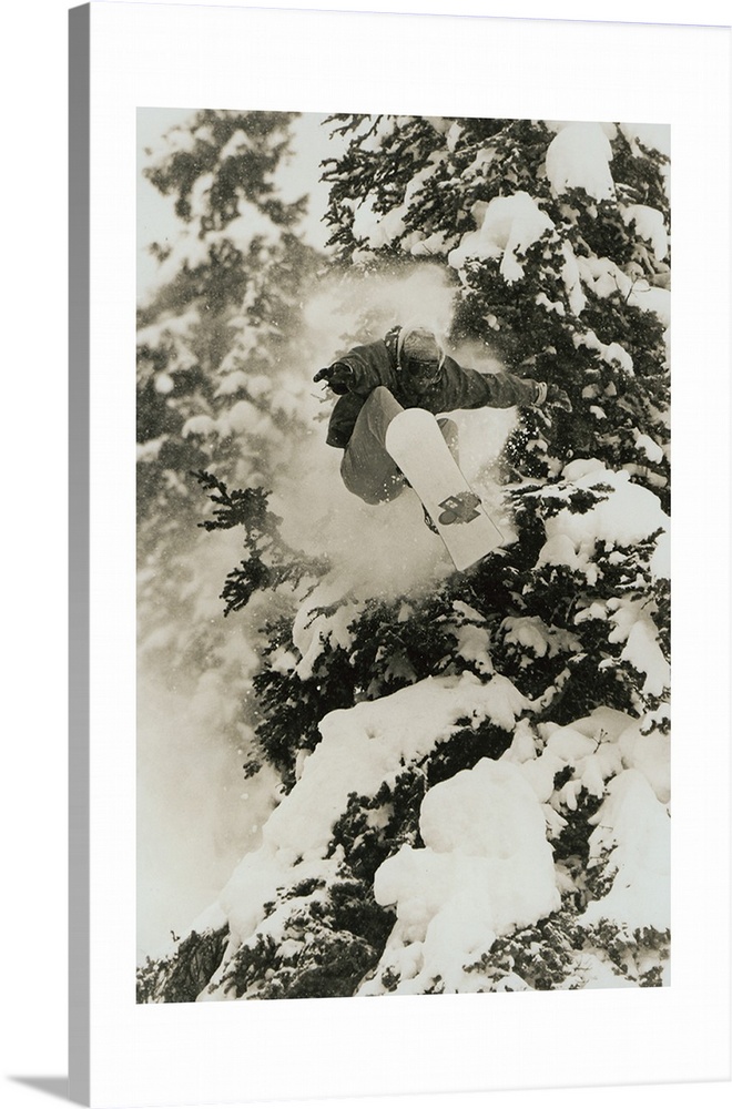 Photograph of Marc Morriset snowboarding over snow covered trees in the Selkirk Mountains, British Columbia, Canada