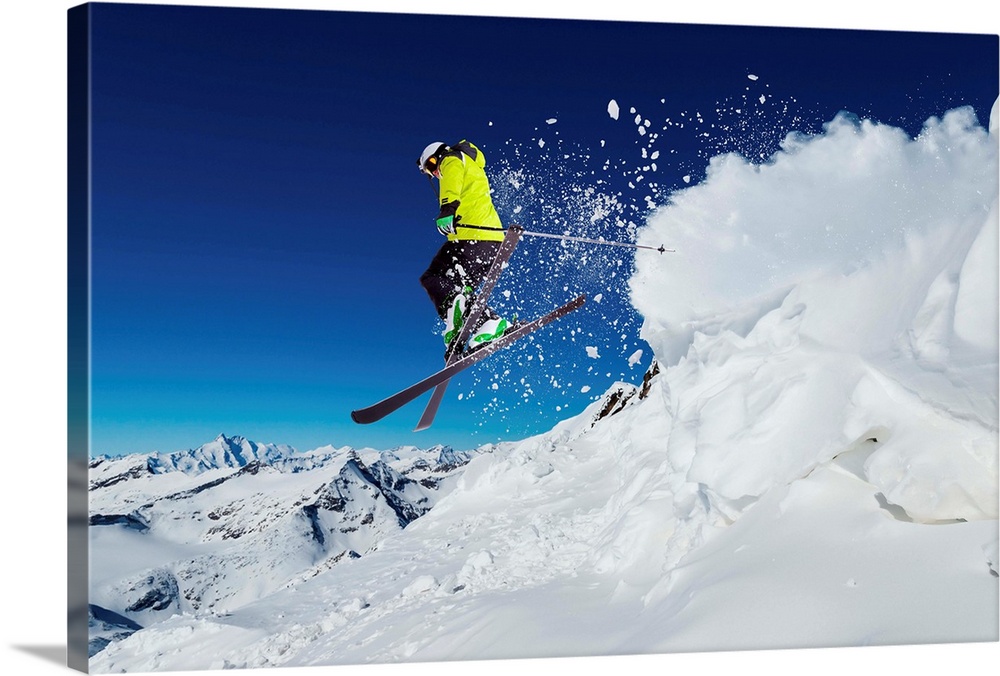 Alpine skier skiing downhill, blue sky in background.