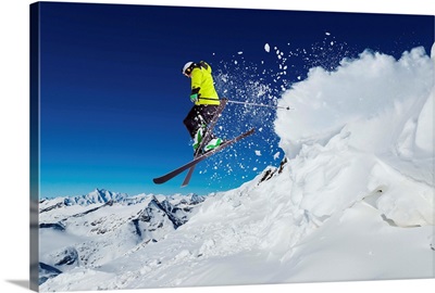 Alpine skier skiing downhill, blue sky in background