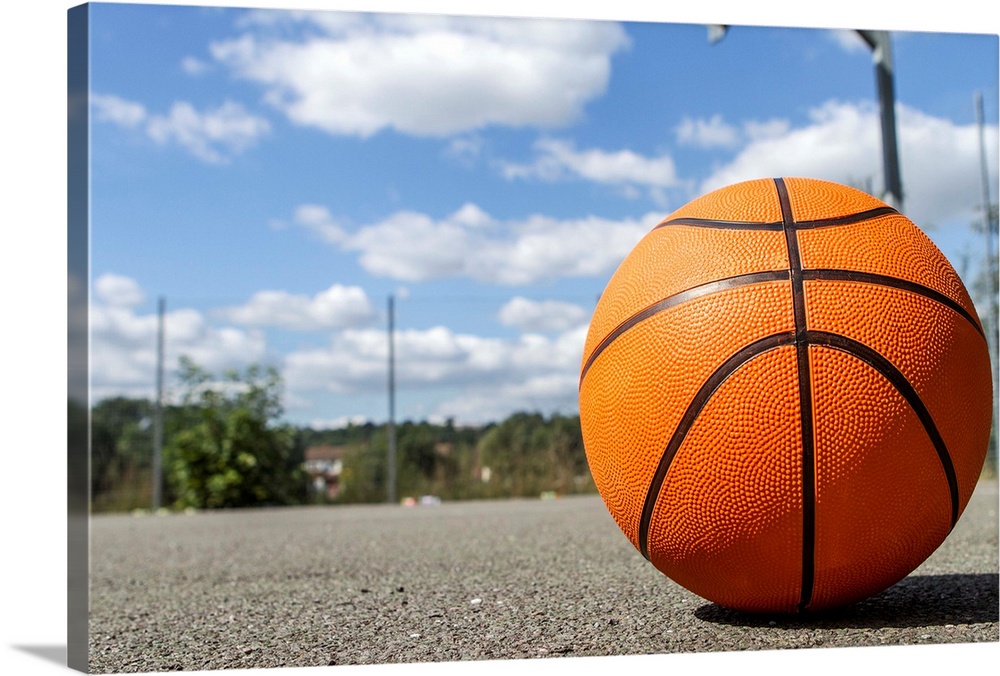 Close up shot of a basketball on a basketball court on a sunny day.