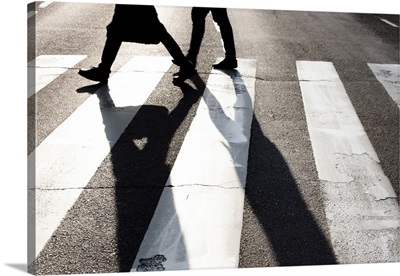 City Zebra Crossing With Two Blurry Walking Pedestrians Making Long Shadows
