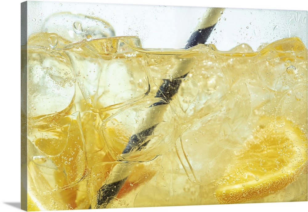 Close up of lemon slices in stirring the lemonade and ice cubes on background. Texture of cooling sweet summer's drink wit...