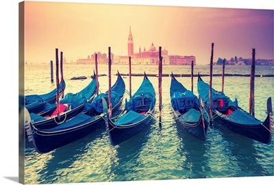Gondolas moored in harbor at sunset in Venice