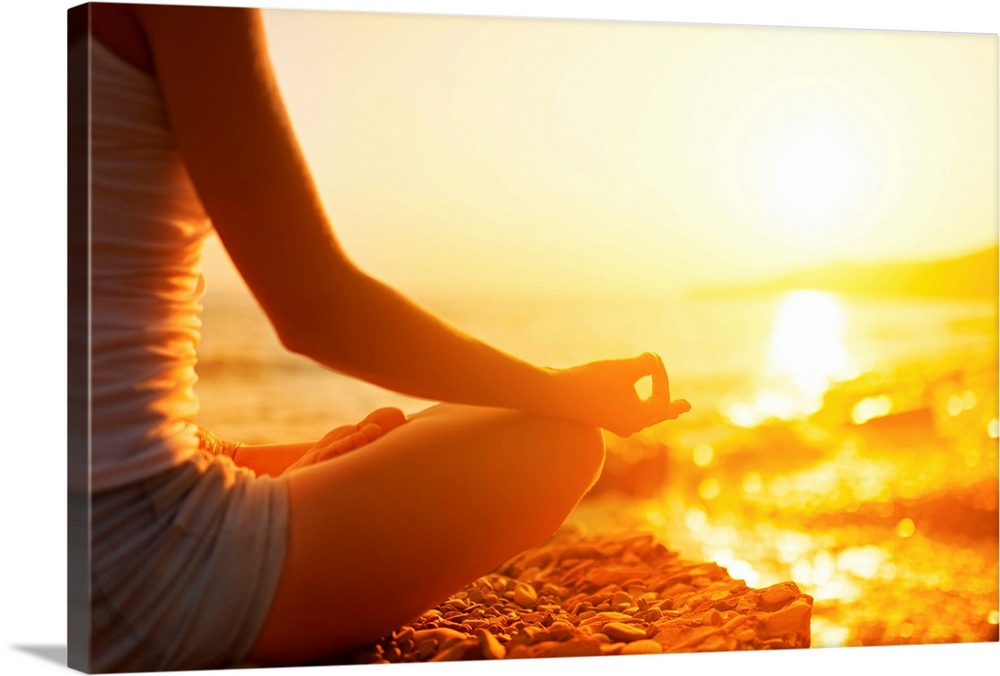 Hand of a woman meditating in a yoga pose on the beach.