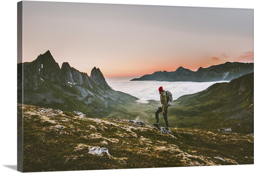 Man backpacker hiking in mountains alone outdoor active lifestyle travel adventure vacations sunset Norway landscape.