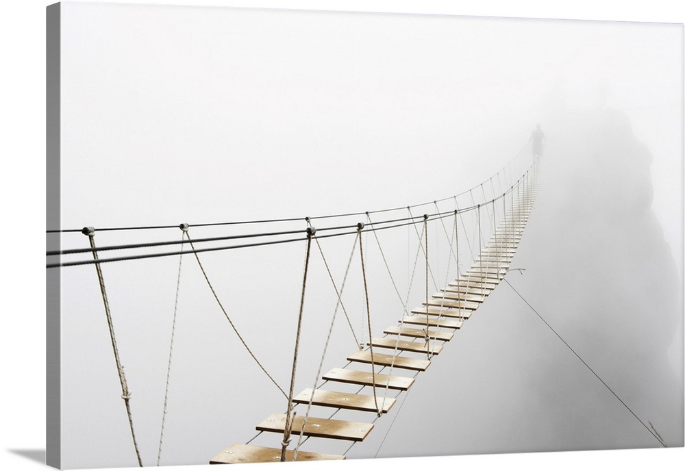 Fuzzy man walking on hanging bridge vanishing in fog. Focus is on the middle of bridge.