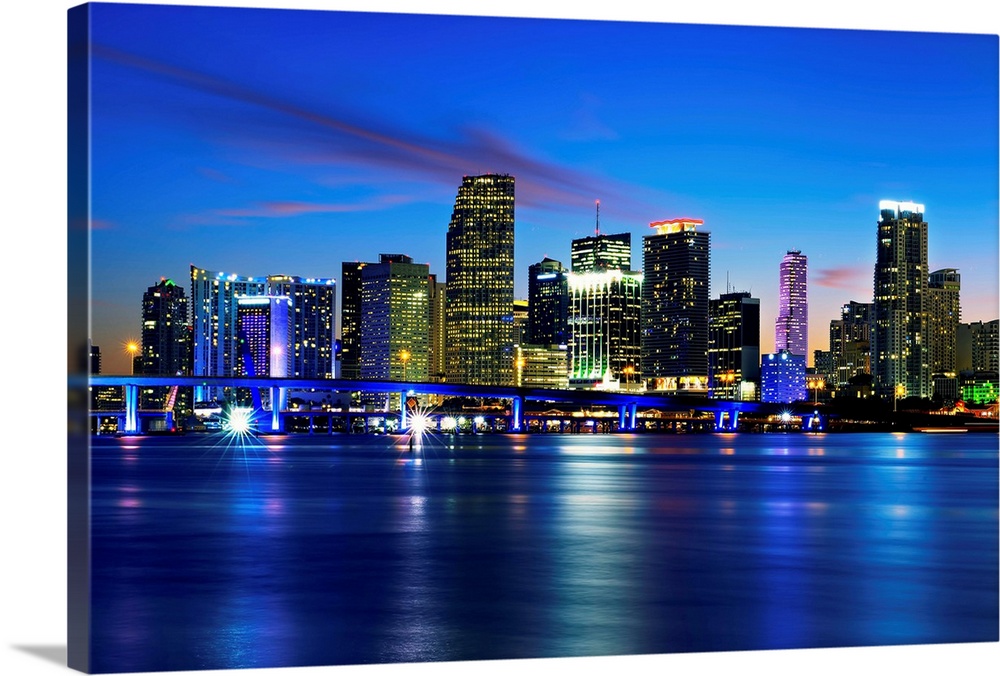 Miami city skyline panorama at dusk with urban skyscrapers over sea with reflection.