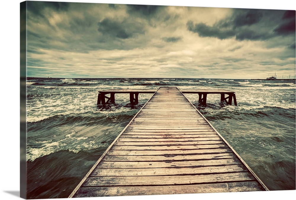Old wooden jetty, pier, during storm on the sea. Dramatic sky with dark, heavy clouds.