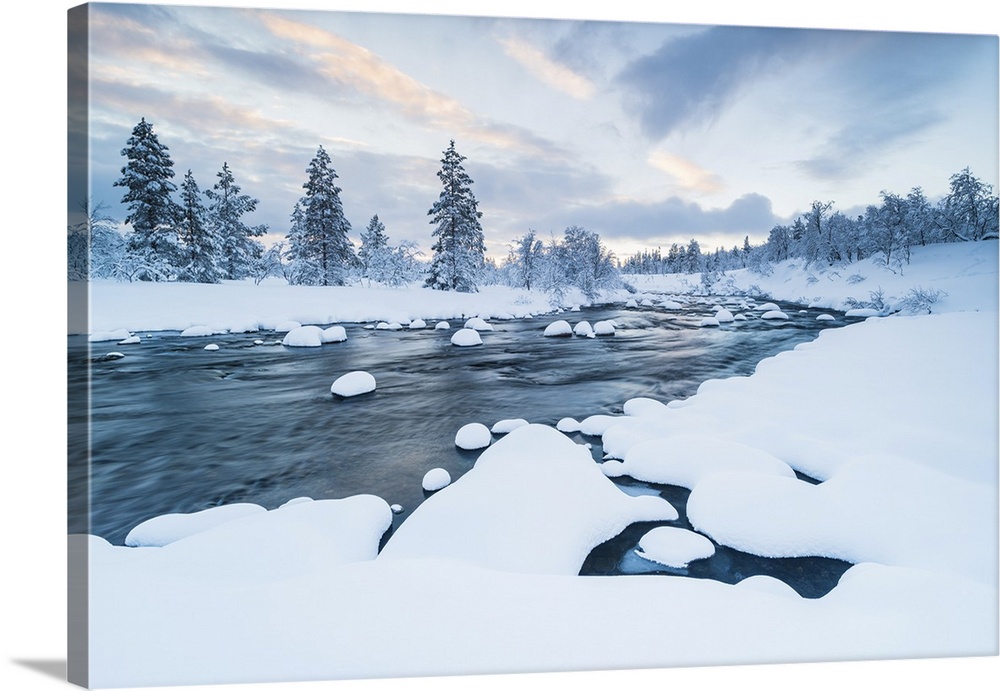 The river with snow in it and a forest near covered with snow in winter in Sweden.