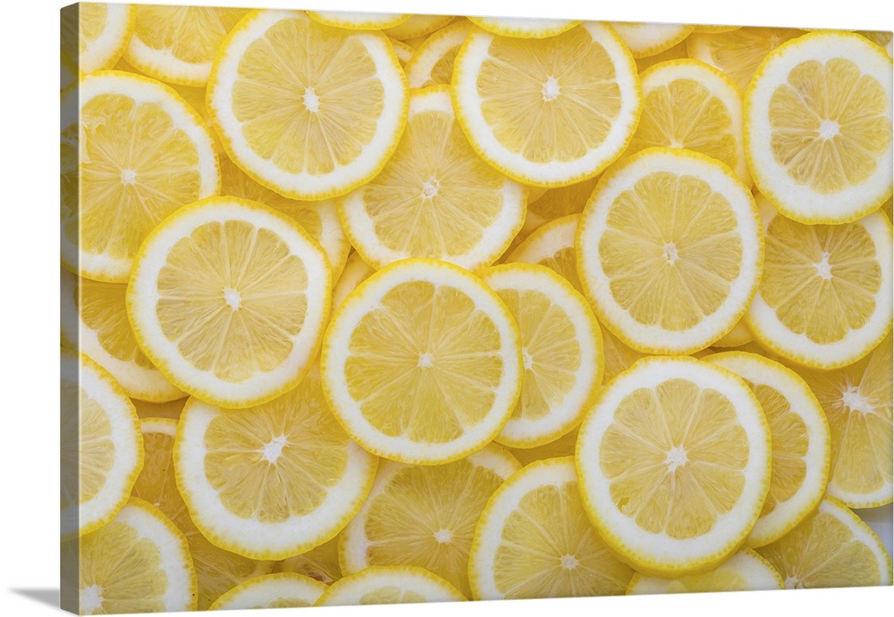 Yellow sliced lemons places on a table overlapping each other. Background texture of fresh yellow fruit.