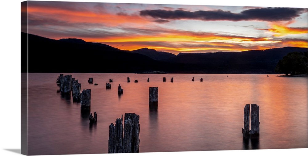 Sunset on Okanagan Lake British Columbia, Canada overlooking abandoned dock pilings and lake rocks.