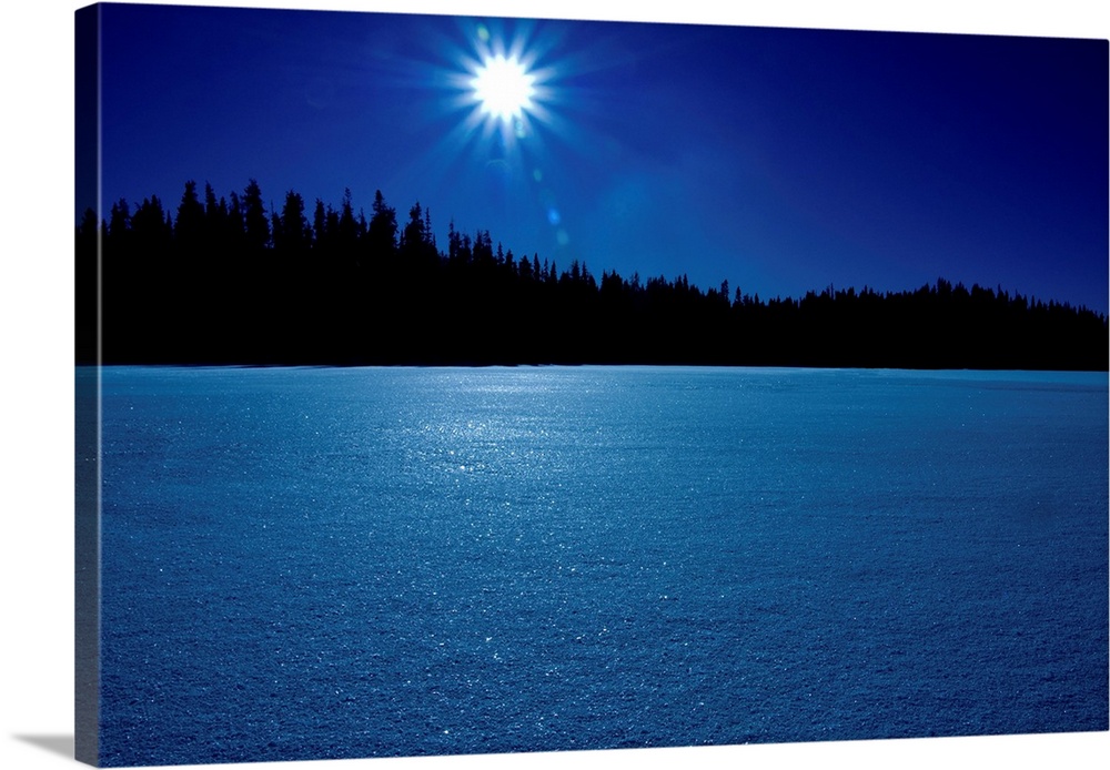 Mid day sun shining over a mountain winter lake in British Columbia, Canada.