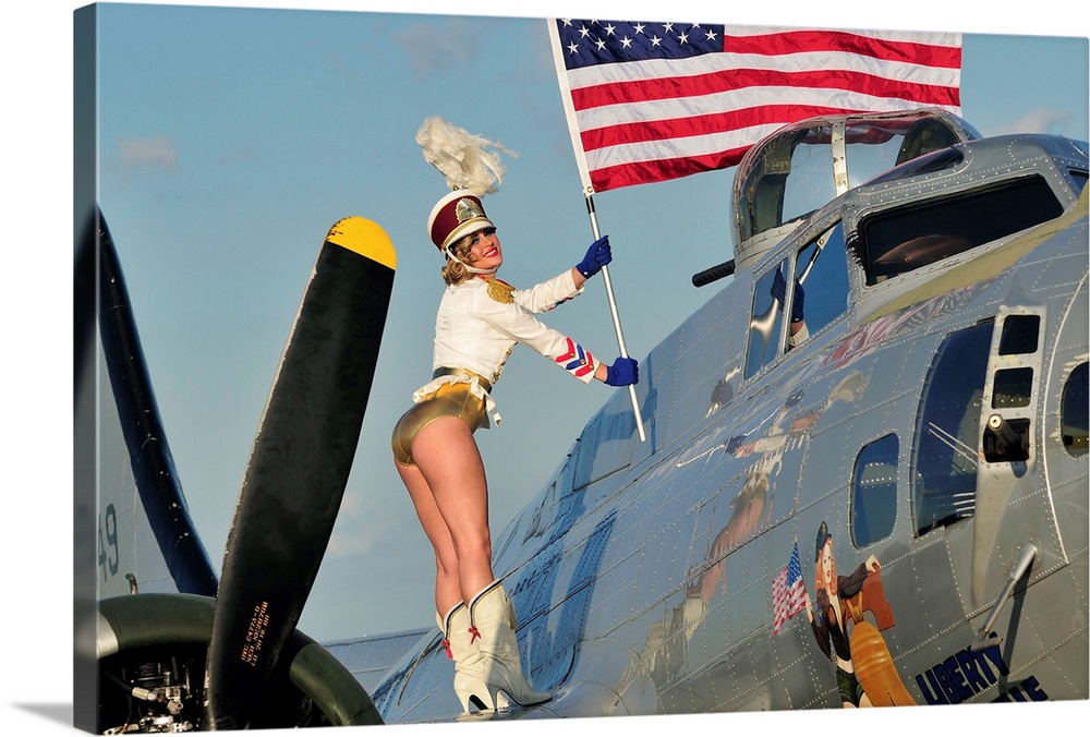 Patriotic 1940's style majorette pin-up girl standing on a B-17 bomber with an American flag.