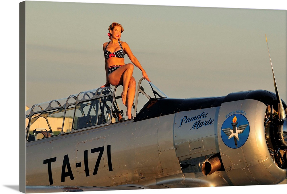 1940's style pin-up girl sitting on the cockpit of a World War II T-6 Texan.