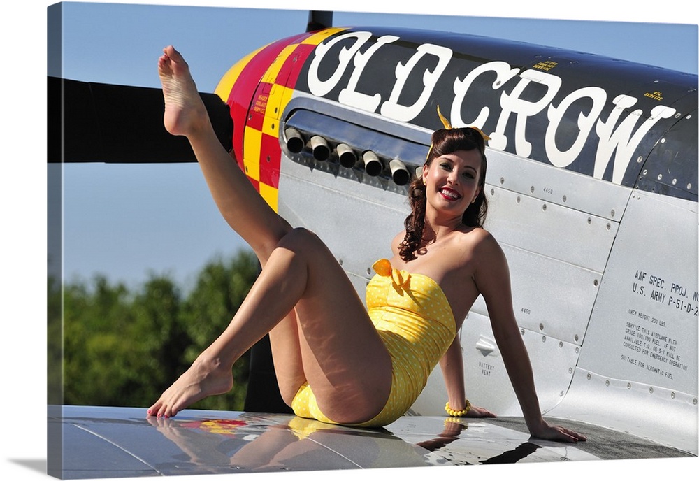 Cute pin-up girl sitting on the wing of a World War II era P-51 Mustang fighter plane.