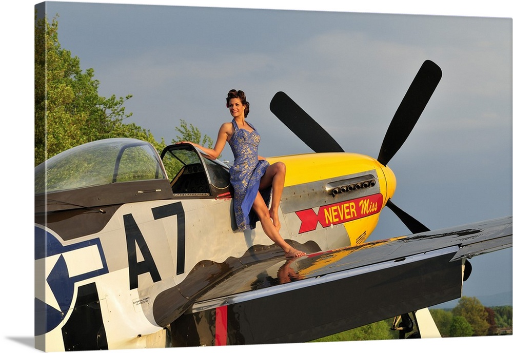 Beautiful 1940's style pin-up girl standing barefoot on the wing of a P-51 Mustang.