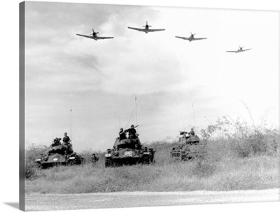 A-1H aircraft make a low level pass over Vietnamese tanks and ground troops