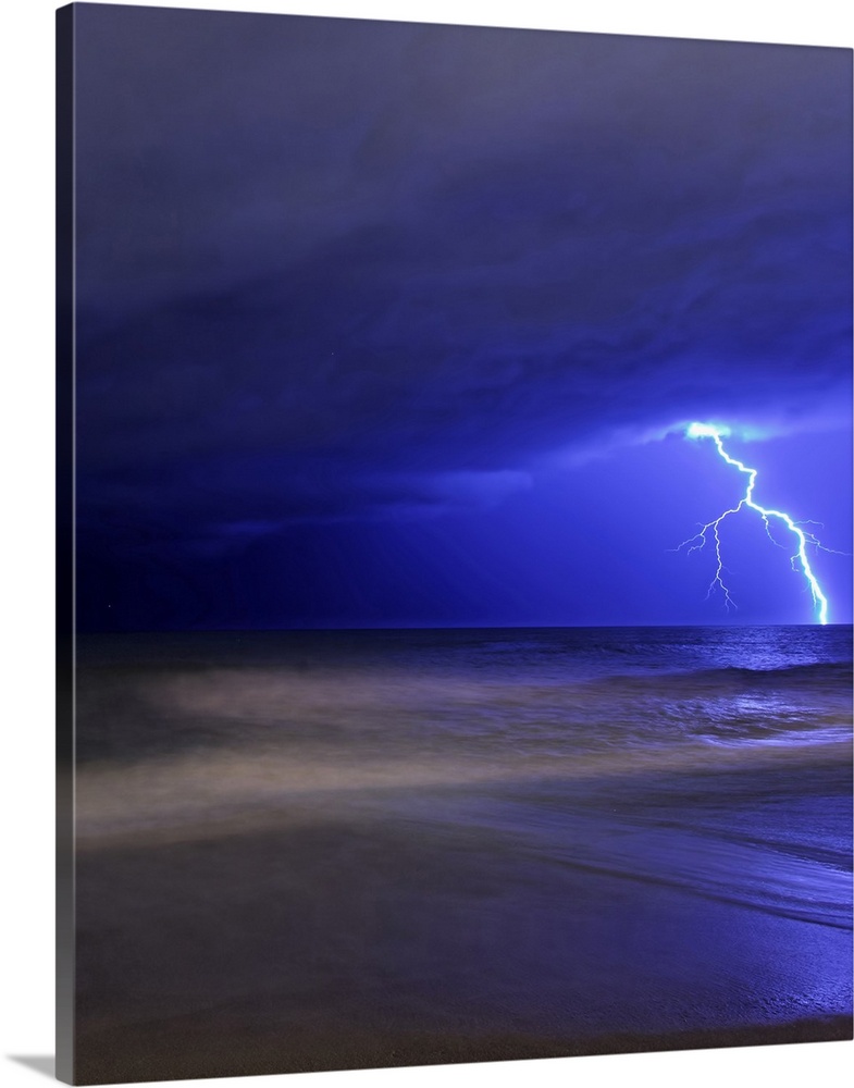 Portrait photograph on a big canvas of a large bolt of lightening illuminating the cloudy night sky, over rough waters in ...