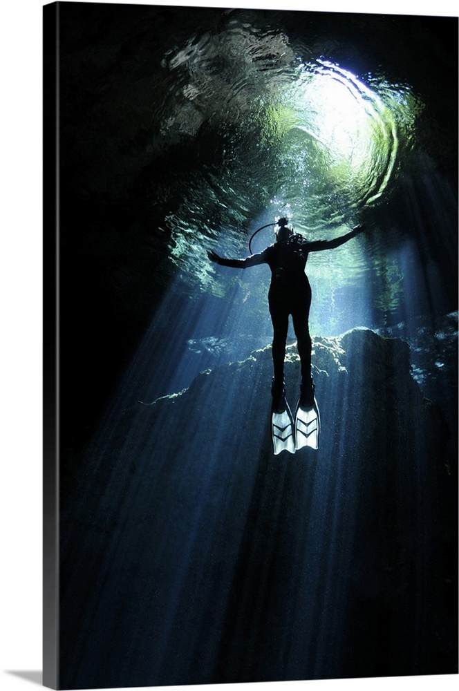 A cavern diver ascends into the light filtering into cenote system at Yucatan Peninsula, Mexico.