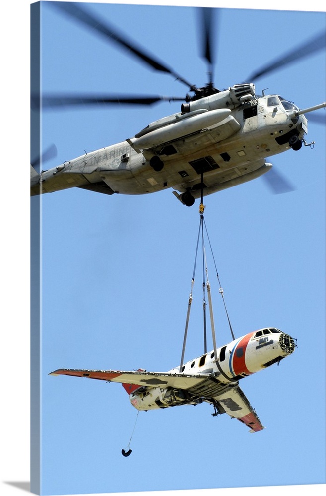 A CH-53 Sea Stallion lifts a HU-25 Guardian Coast Guard aircraft.
