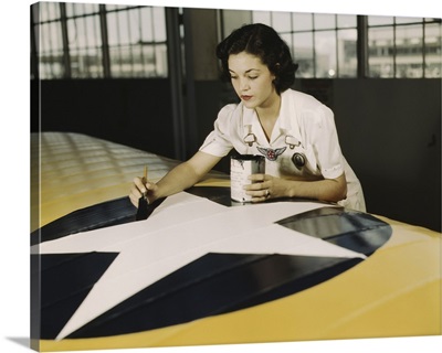 A civil service worker paints the American insignia on a repaired Navy plane wing