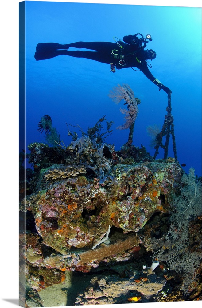 A diver hangs on to a piece of WW2 stern wreckage, West Papua, Indonesia.