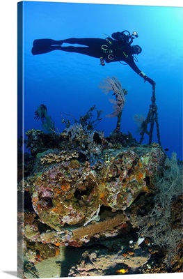 A diver hangs on to a piece of WW2 stern wreckage, West Papua, Indonesia