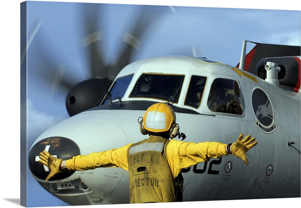 A flight deck director signals the pilot of an E-2C Hawkeye to spread his wings.