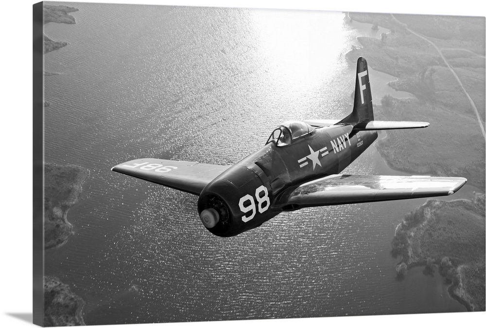 A vintage military aircraft is photographed in black and white as it flies over a large body of water.