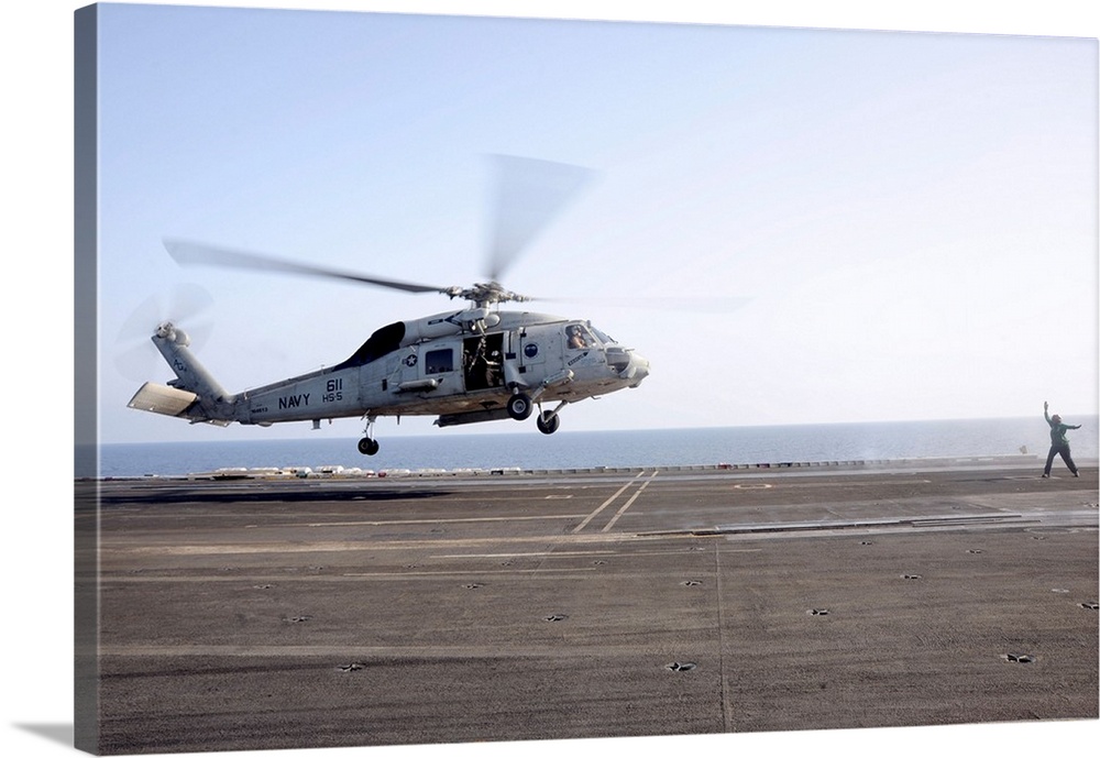 A helicopter landing signalman directs an SH-60F Sea Hawk.