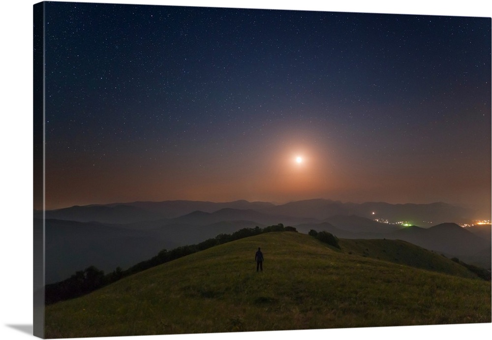 A lone man stands on the mountains at night under the moon, Sudak, Crimea.