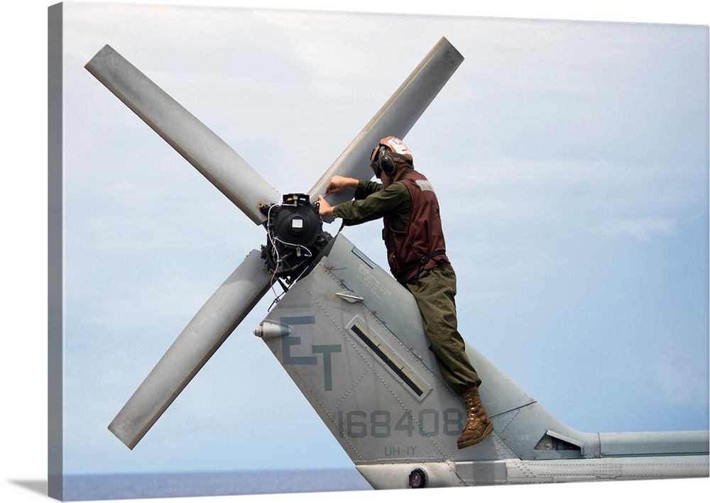 A Marine conducts maintenance on the tail of an UH-1N Huey helicopter.