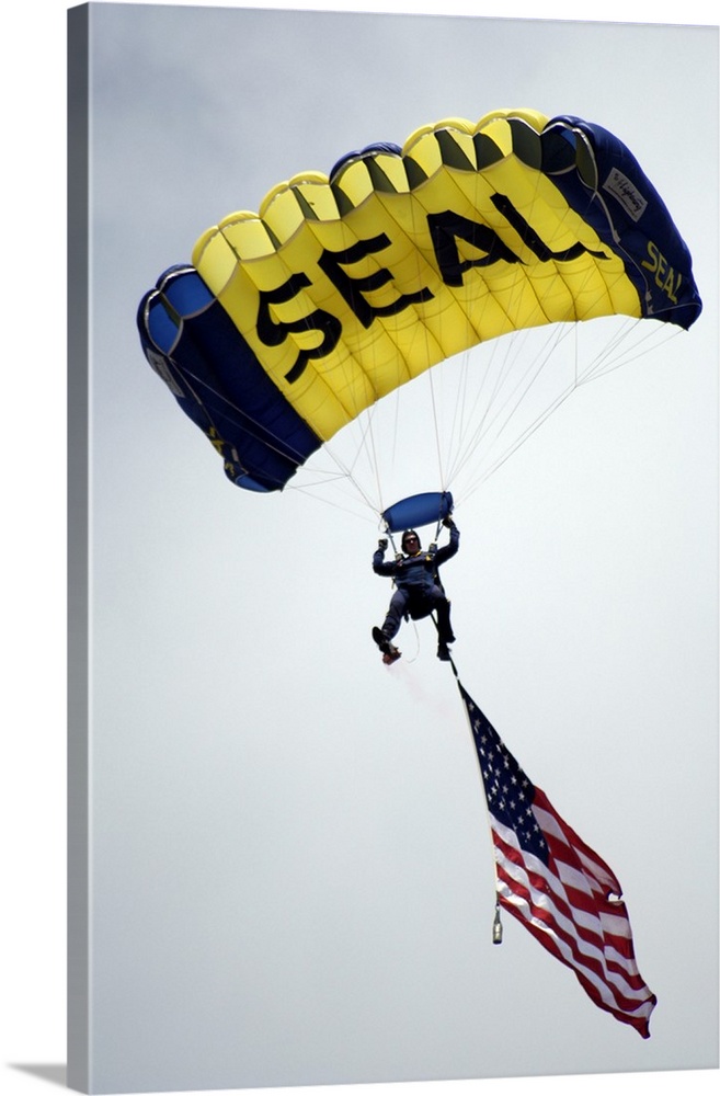 A member of the U.S. Navy Parachute Team descend through the sky with the American flag.