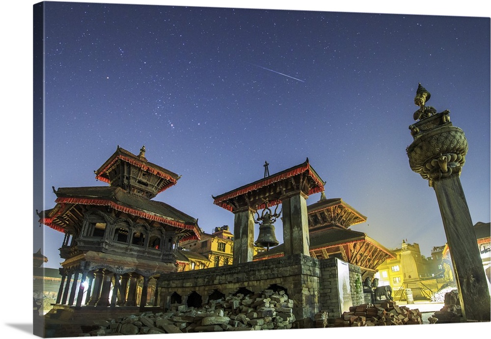 Above lights of the Bhaktapur Durbar Square of Nepal, a meteor streaks the sky next to the stars of Orion during the peak ...