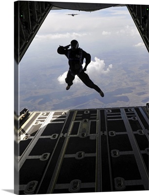 A paratrooper salutes as he jumps out of a C-130J Super Hercules