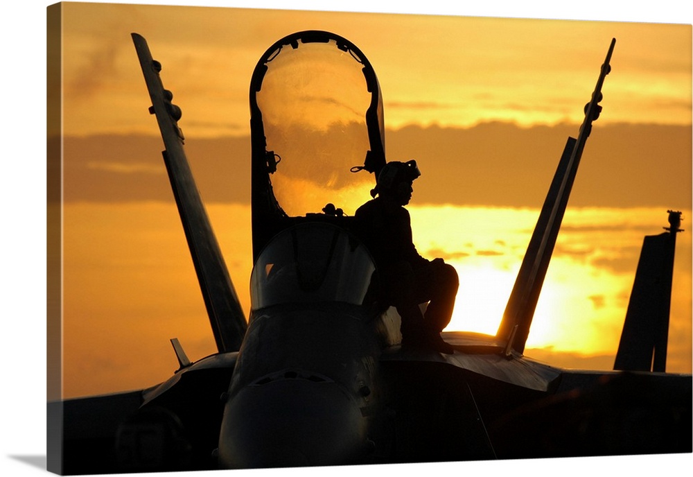 A plane captain enjoys a sunset from atop an F/A-18 Hornet.
