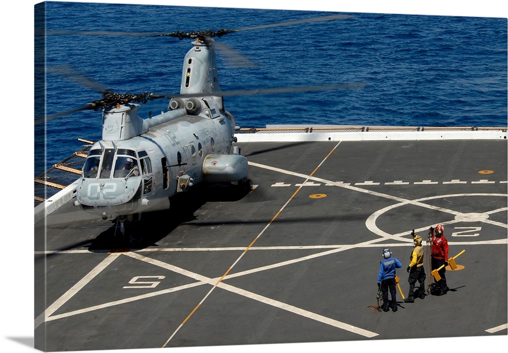 A plane captain signals to a CH-46E Sea Knight helicopter.