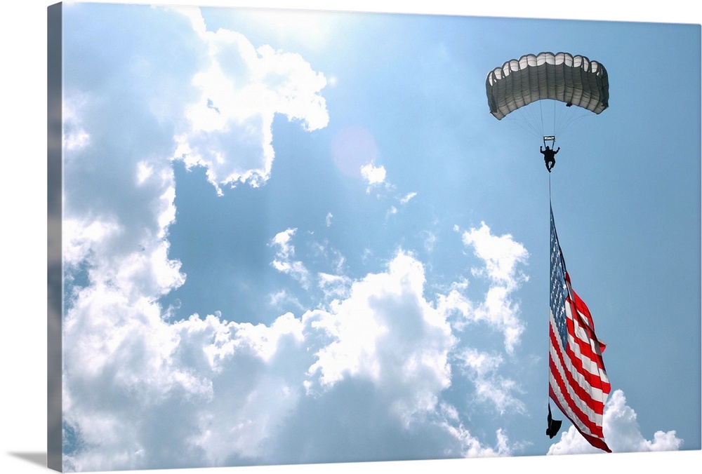 A skydiver carries a U.S. flag while descending through the sky.