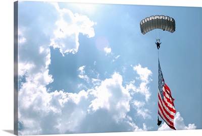 A skydiver carries a US flag while descending through the sky