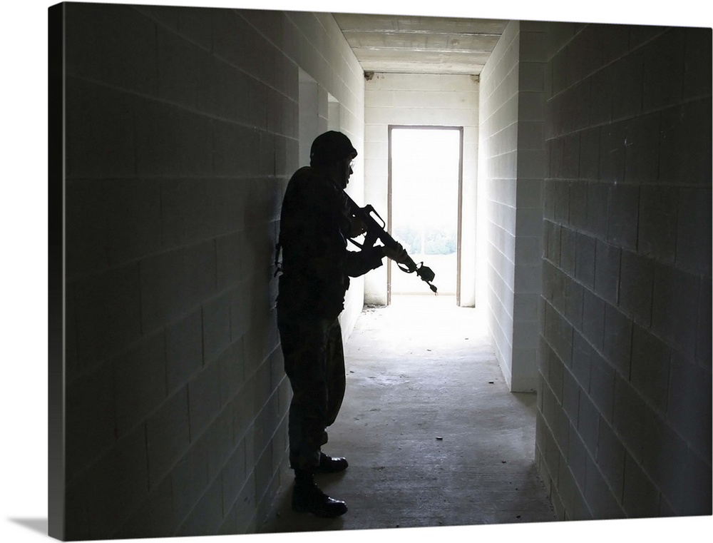 A soldier clears a hallway at a Military Operation in Urban Terrain training facility