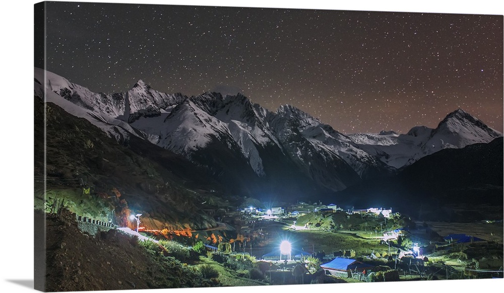A starry night in Laigu village, Tibet, China. Moonlight illumates the snow mountains in the background.