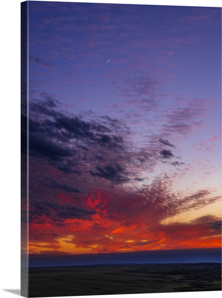 A Sunset Sky With The Waxing Crescent Moon Amid Colorful Clouds Over A Prairie