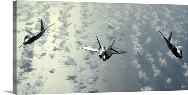 A three-ship formation of F-22 Raptors flies over the Pacific Ocean ...
