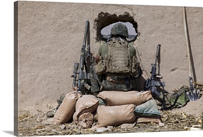 A U.S. Marine sniper observes his sector at a patrol base near Sangin, Afghanistan