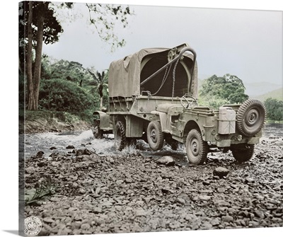 A U.S. military truck with wrecker mount towing a jeep, 1942